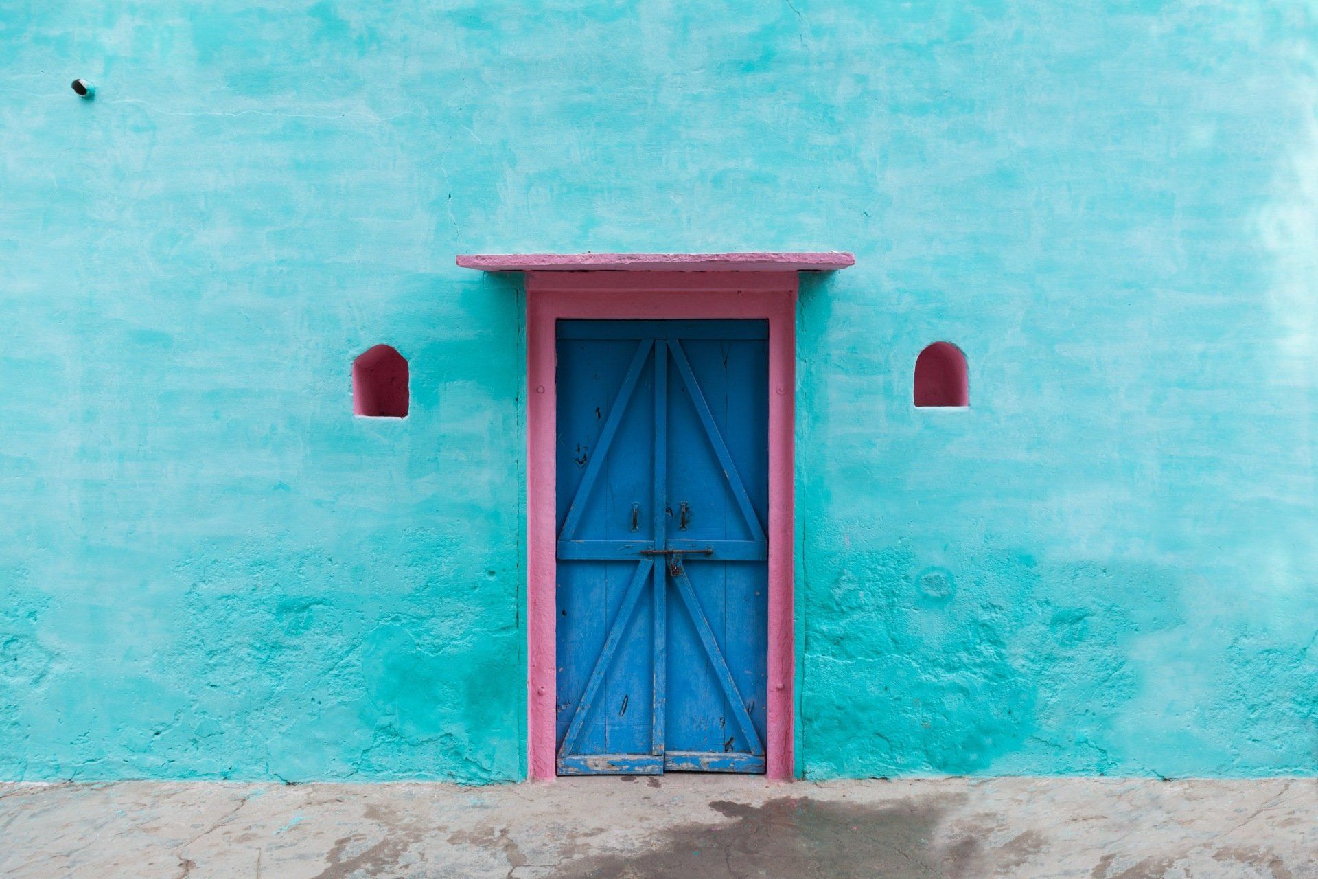 A blue wall with a pink door on it.
