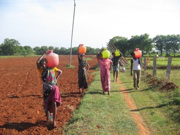 A group of people carrying buckets of water on their heads