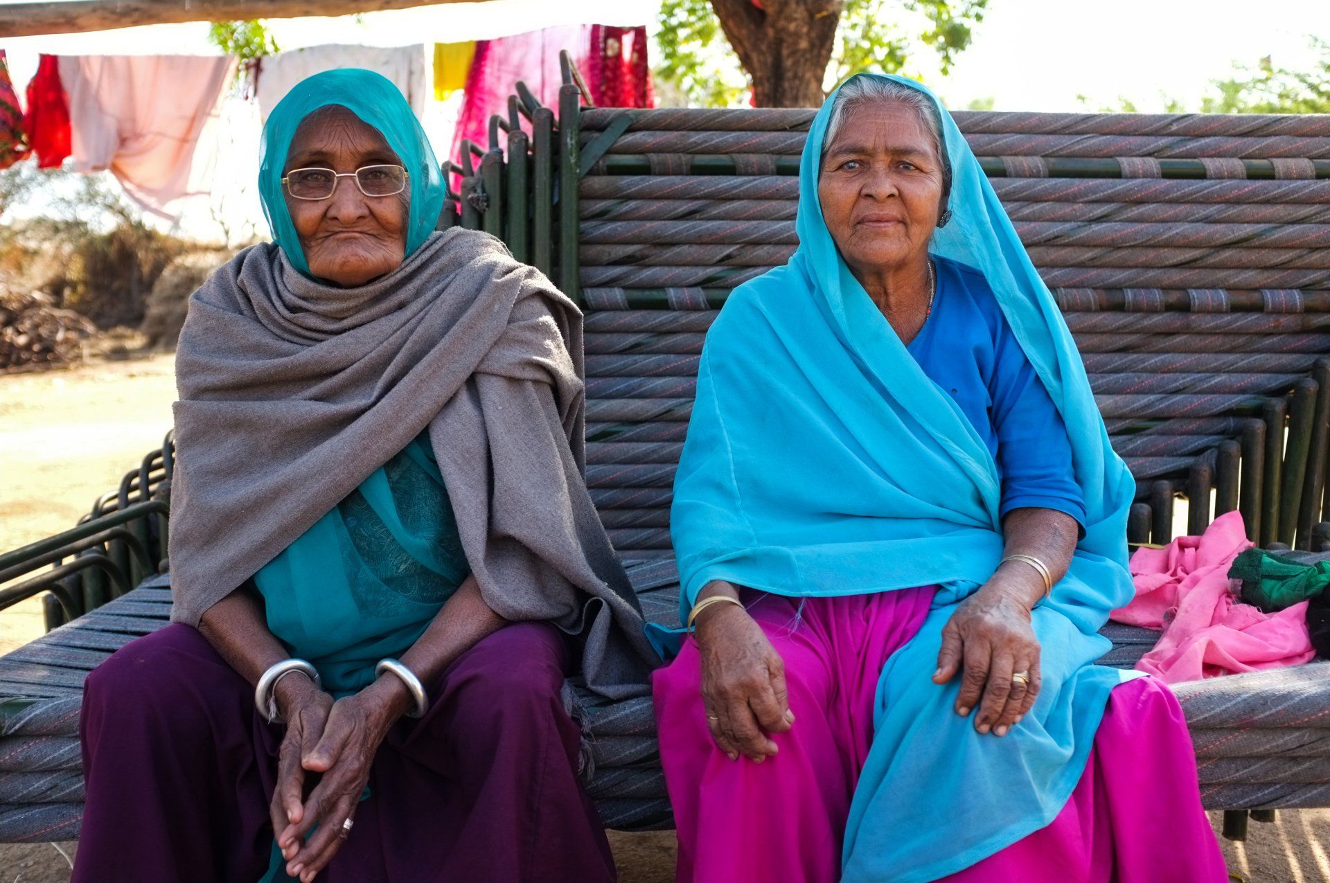 Two women are sitting next to each other on a bench.