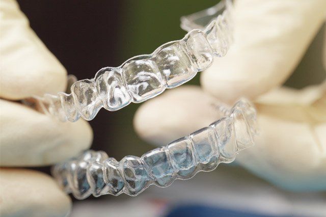 dentist holding mouth guard with gloves
