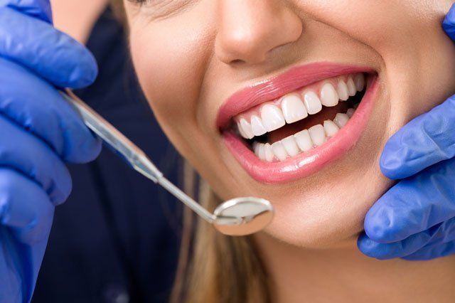 dentist checking woman's smile with dental mirror