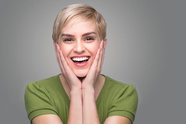 smiling woman smiling woman with hands on face in green top