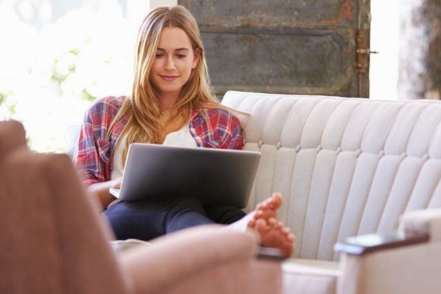 writing a review woman on couch at home on laptop writing a review