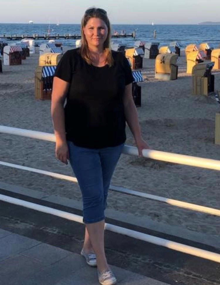Eine Frau in einem schwarzen Hemd steht an einem Strand