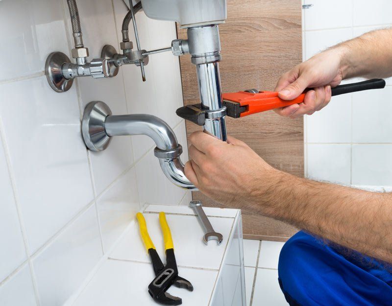 Close-up Of Male Plumber Fixing Sink In Bathroom Close-up Of Male Plumber Fixing Sink In Bathroom