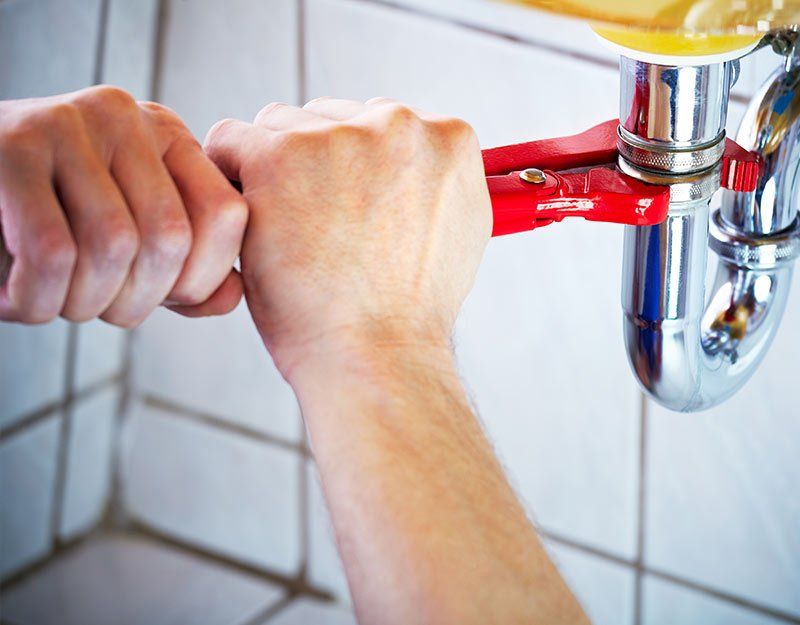 Plumber hands holding wrench for cleaning a sink in bathroom Plumber hands holding wrench for cleaning a sink in bathroom