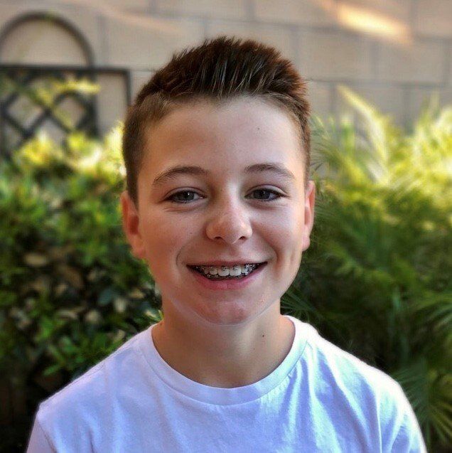 A young boy with braces on his teeth is smiling for the camera.