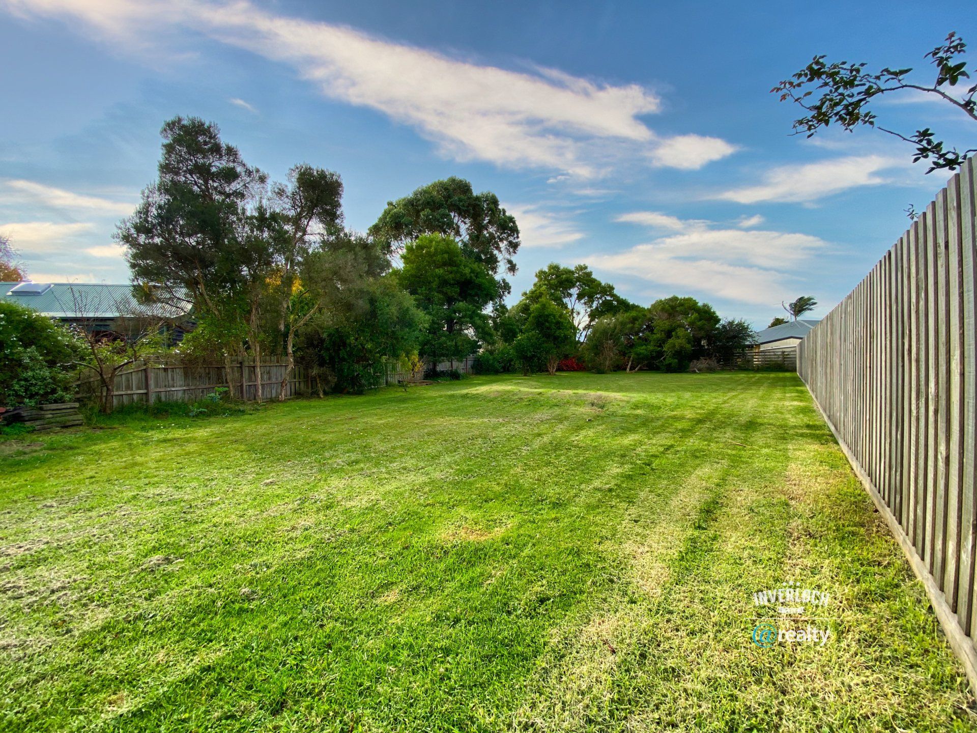 A fence surrounds a lush green field with trees in the background.