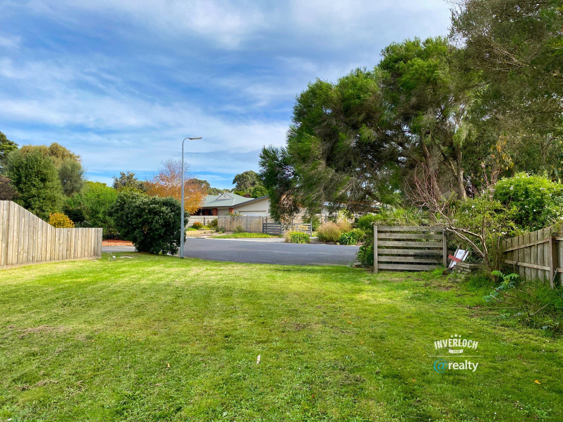 A lush green yard with a wooden fence and a house in the background.