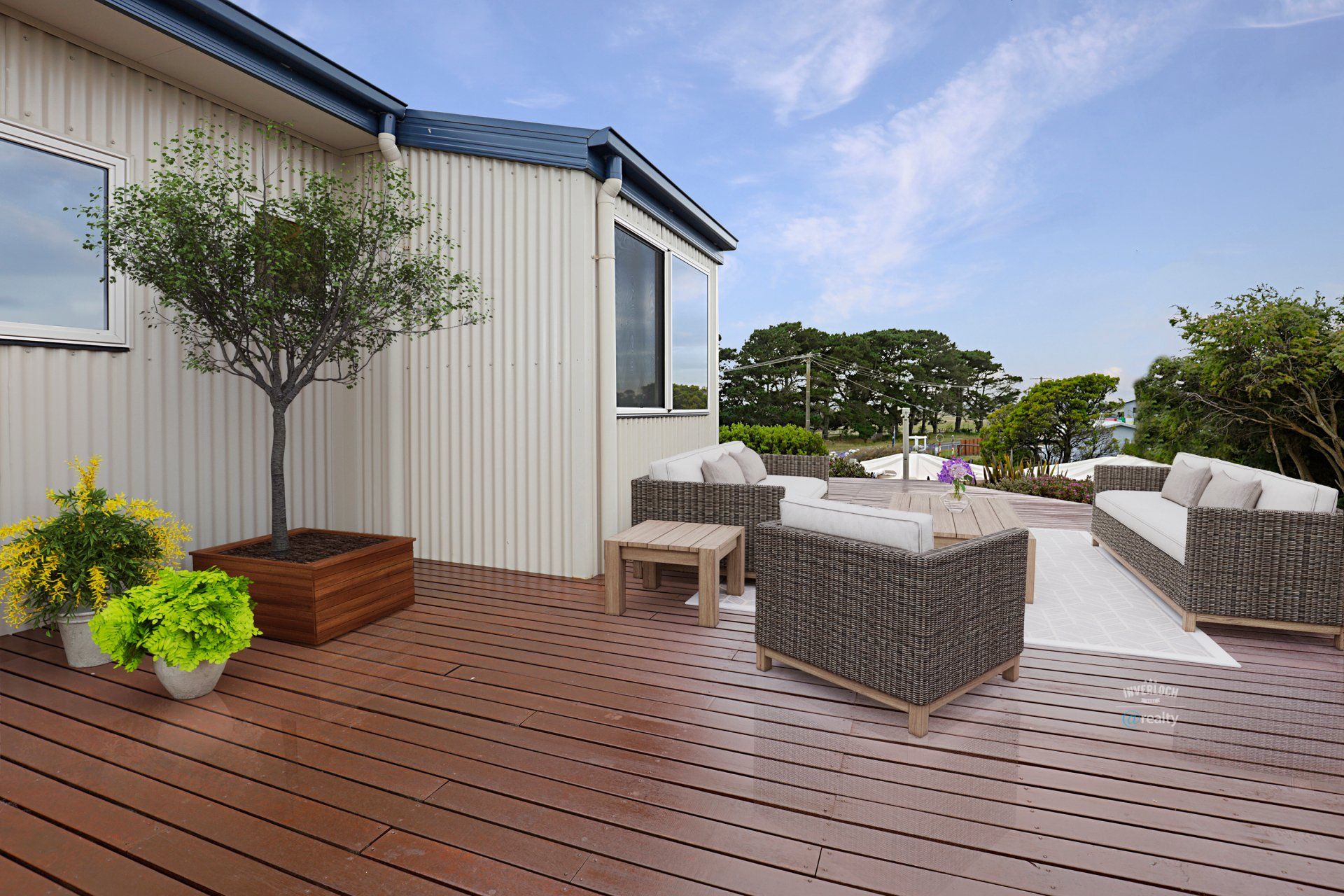 A wooden deck with a couch and chairs on it in front of a house.