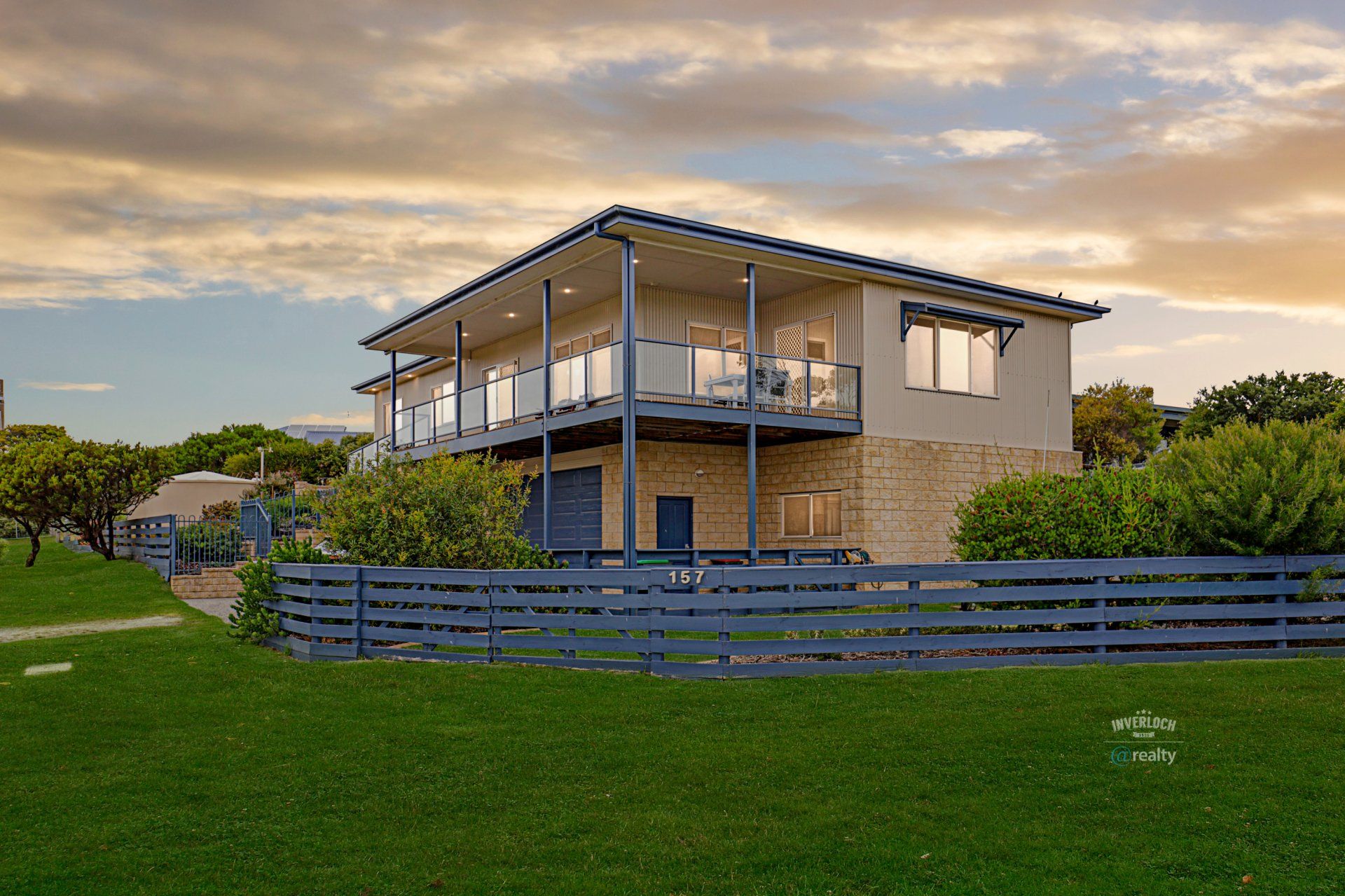 A large house with a fence around it is sitting on top of a lush green field.