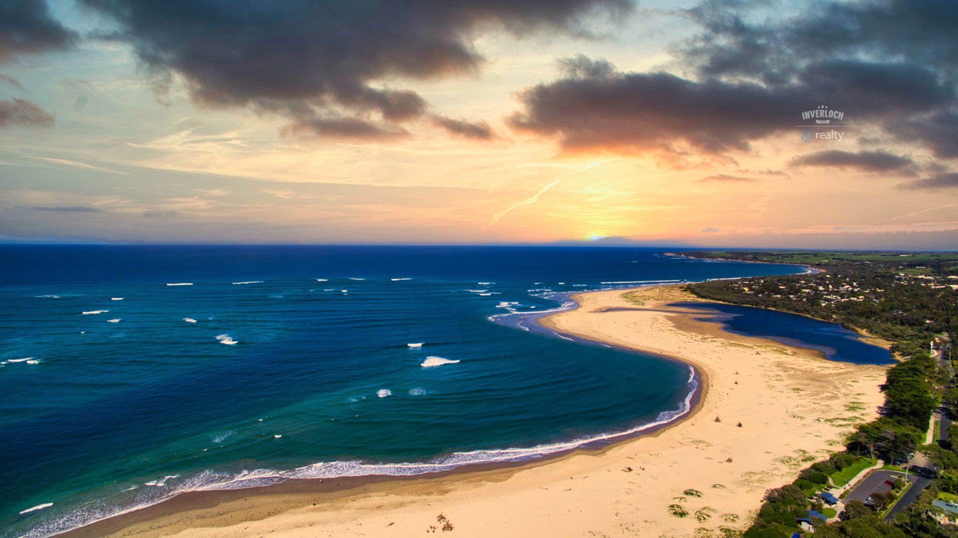 An aerial view of a beach with a sunset in the background.