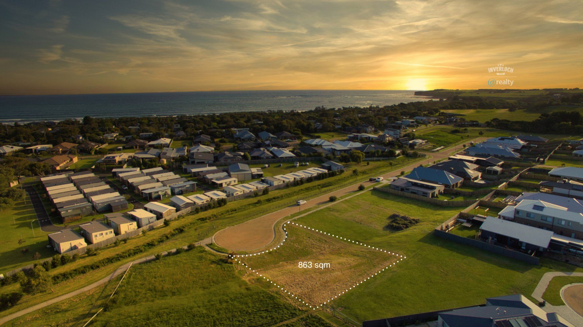 An aerial view of a residential area near the ocean at sunset.