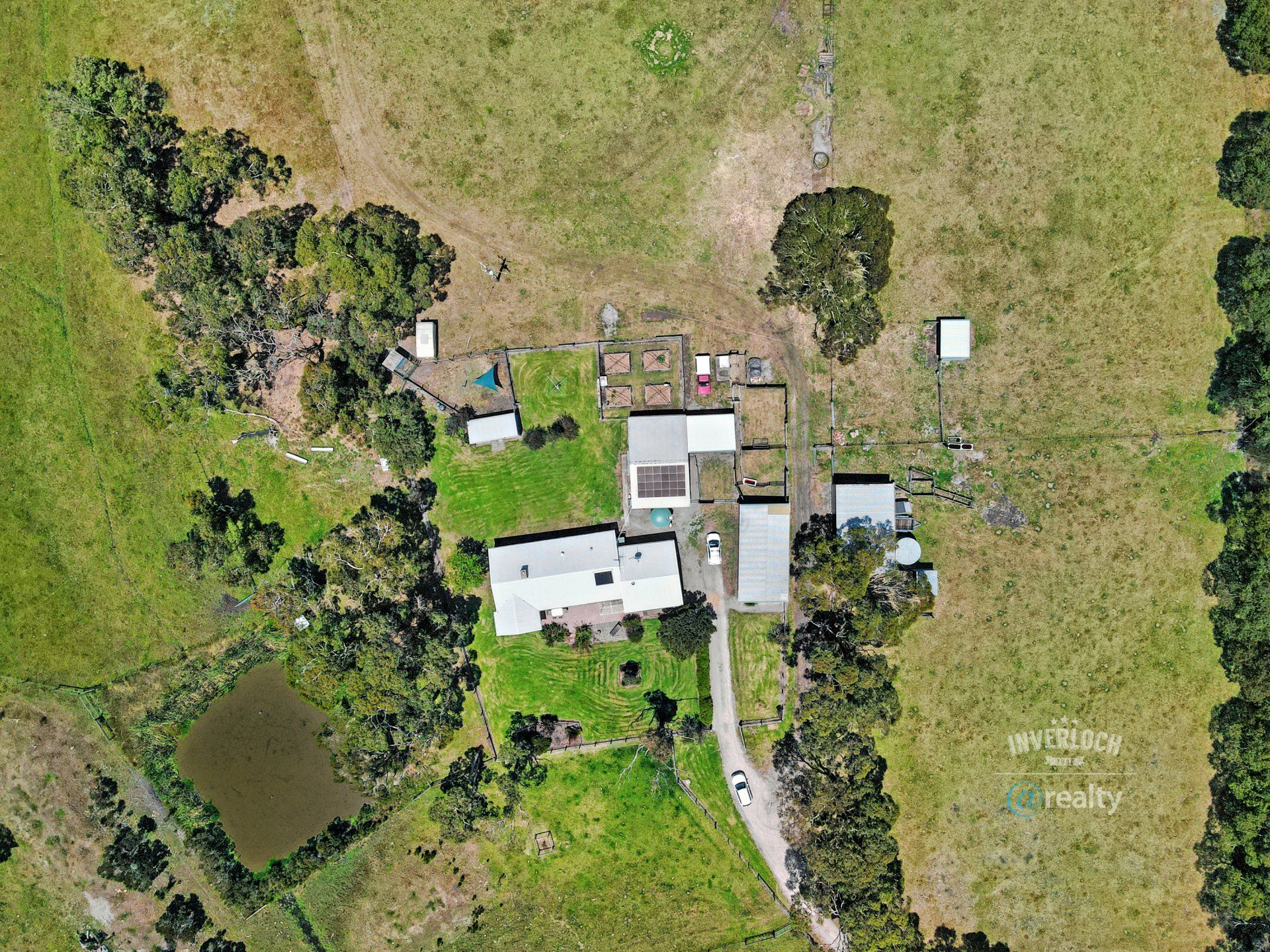 An aerial view of a farm with a house in the middle of a field surrounded by trees.