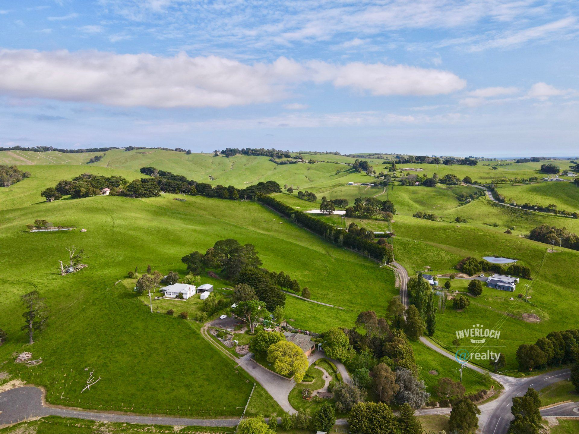 An aerial view of a lush green field with trees and a road.