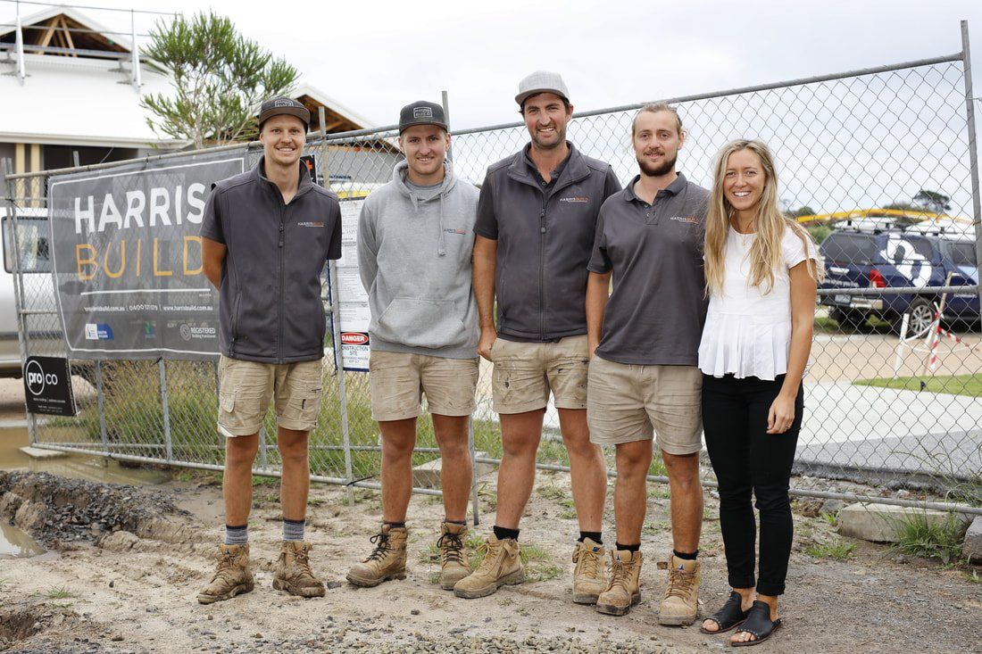 A group of people standing next to each other in front of a fence.