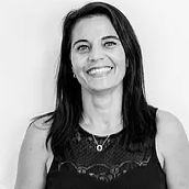 A woman in a black tank top and necklace is smiling in a black and white photo.