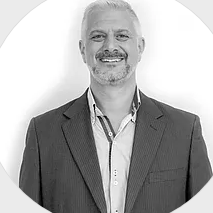 A man with a beard is wearing a suit and smiling in a black and white photo.