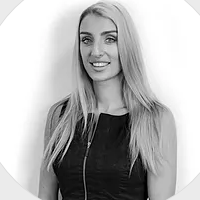 A woman in a black dress is smiling in a black and white photo.