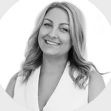 A woman in a white vest is smiling in a black and white photo.
