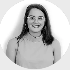 A woman wearing glasses and hoop earrings is smiling in a black and white photo.