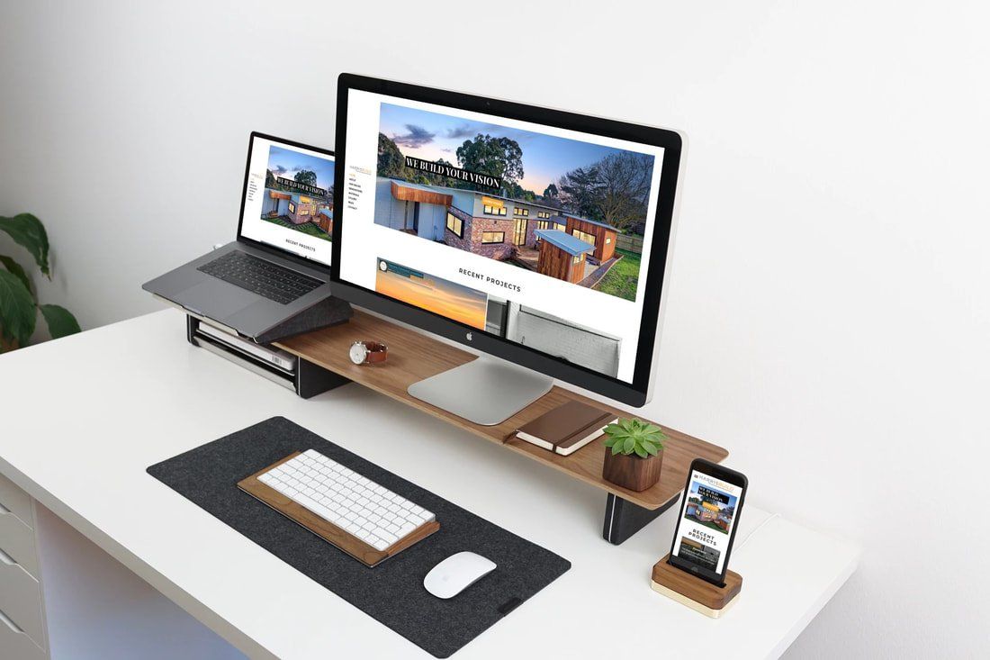 A computer monitor is sitting on top of a desk next to a laptop and a cell phone.