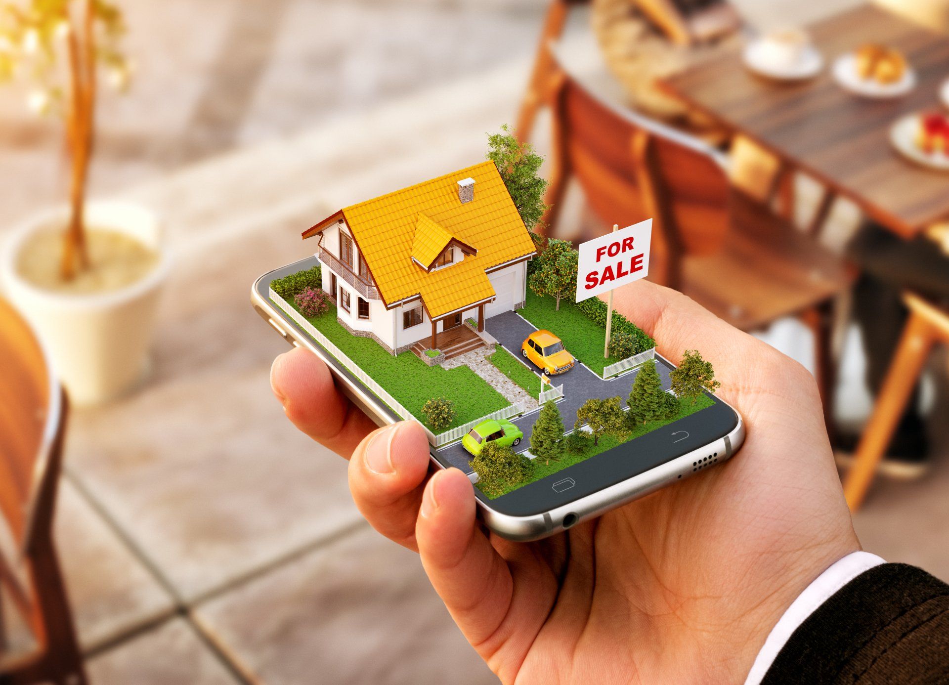 A person is holding a cell phone with a house on the screen.