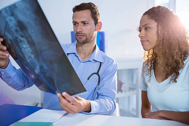 A Chiropractor Examining The XRAY Result — Hampden, ME — Baker Family Chiropractic A Chiropractor Examining The XRAY Result — Hampden, ME — Baker Family Chiropractic