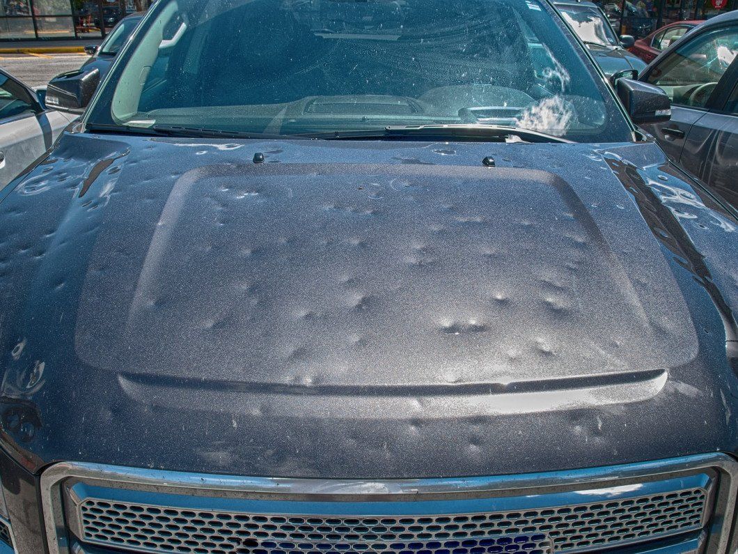 Dust-covered black SUV hood in a parking lot