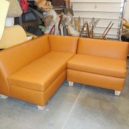 Orange leather sectional sofa in a workshop setting.