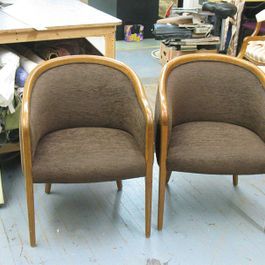 Two brown upholstered chairs with wooden frames sit side by side in a room.