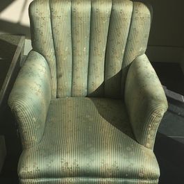 Green upholstered armchair with vertical striped back and patterned fabric.