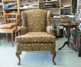 Wingback armchair with patterned fabric in front of shelves.