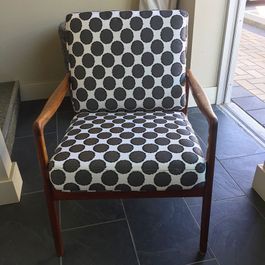 Armchair with a polka-dot pattern seat and back, wooden frame.