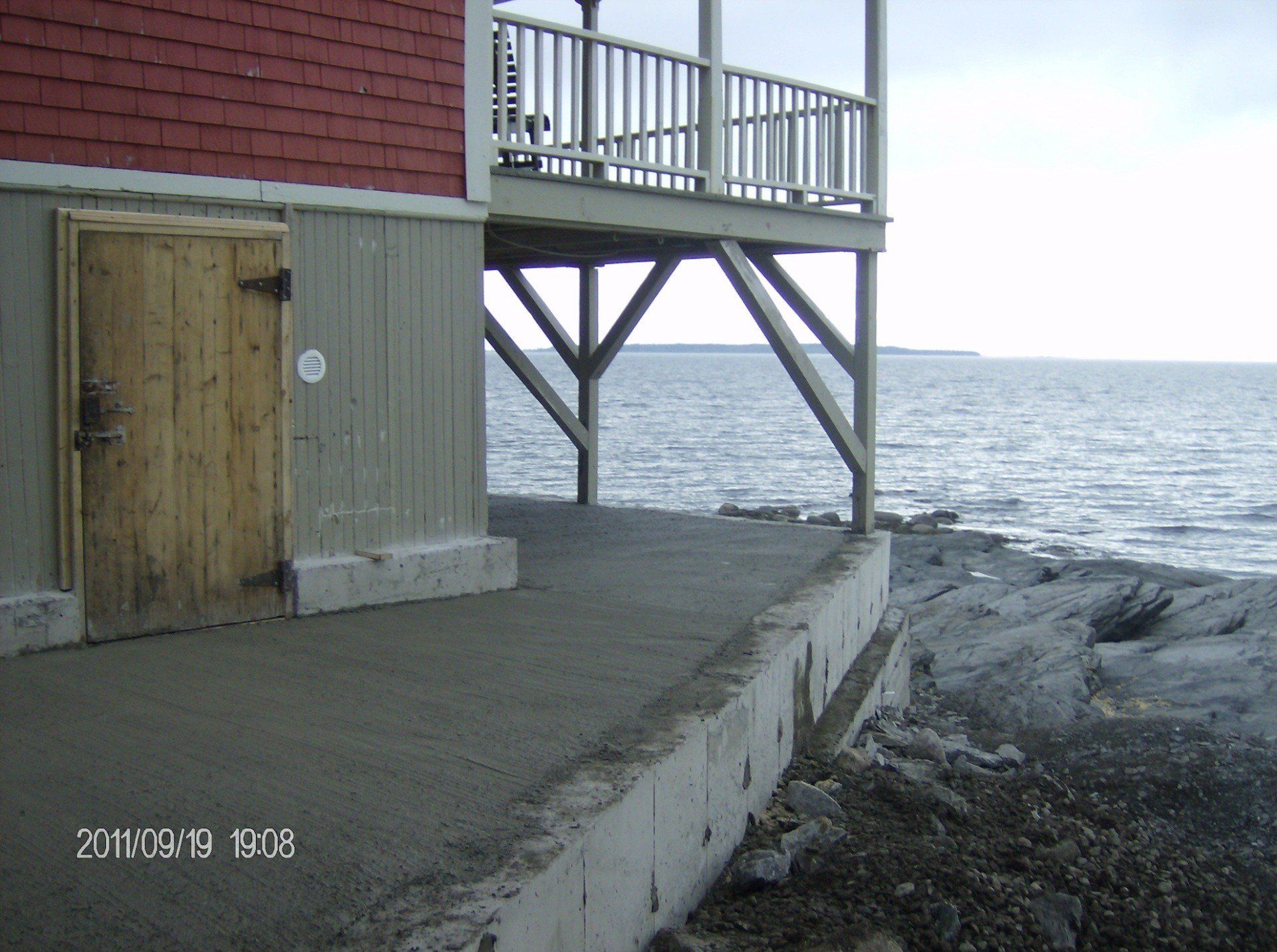 maison avec balcon sur dalle ciment en bordure d'un lac