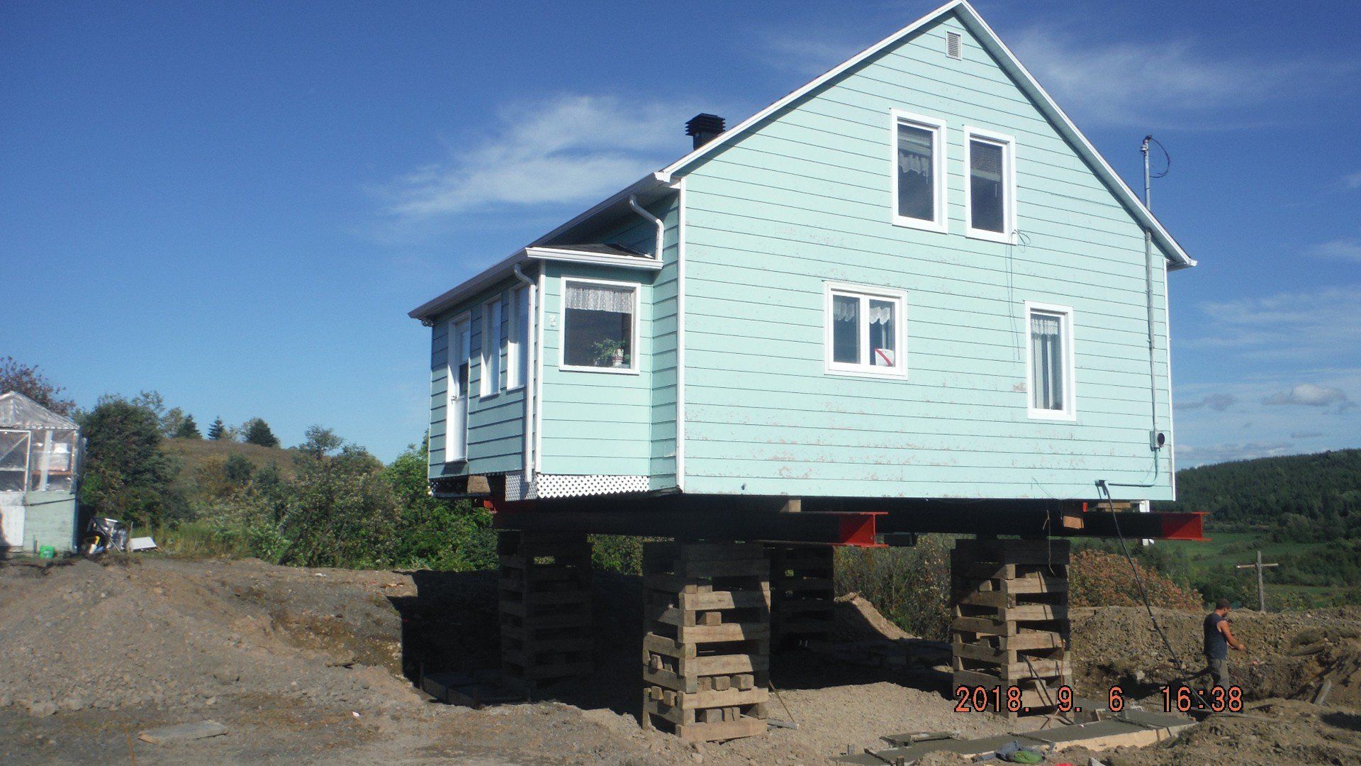 maison turquoise soulevée sur piliers de bois
