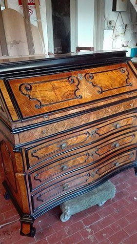 un mobile antico in legno con dei cassetti e disegni