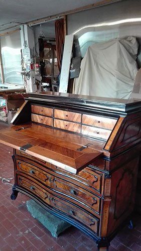 un mobile in legno con dei cassetti e disegni in una