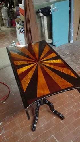 un tavolino in legno con il top di color giallo e bordeaux in una falegnameria