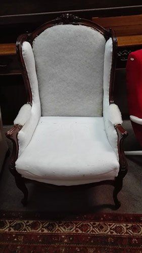 una poltrona in legno con i cuscini di color bianco