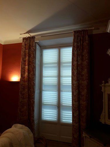 una finestra con delle bianche e di color bordeaux