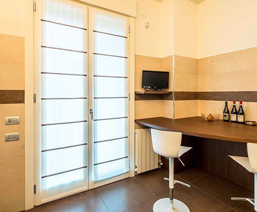 un tavolo a muro in legno e due sgabelli di color bianco