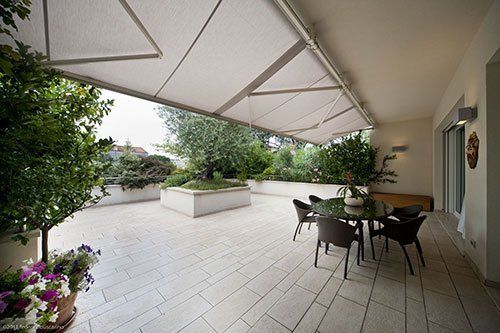 una terrazza con un tavolo, delle sedie e un tendone