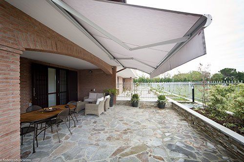 una veranda con un tendone e un pavimento in pietra