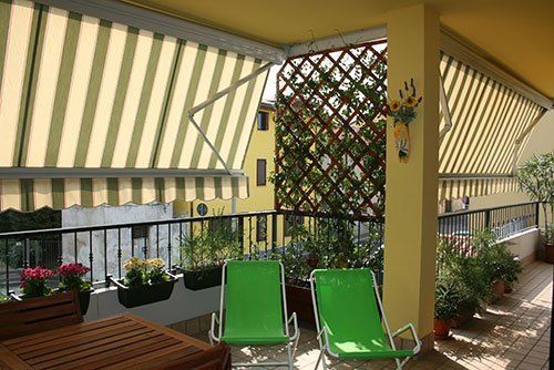 una terrazza con dei vasi di fiori, due sdraio e un tendone