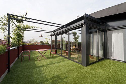 una terrazza con prato e una veranda con delle tende bianche