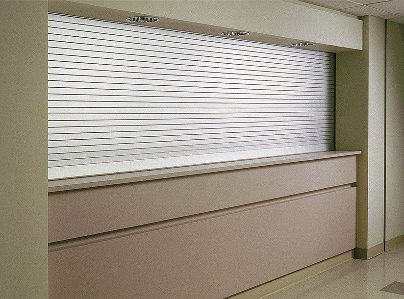 Closed white service counter window in a beige interior hallway