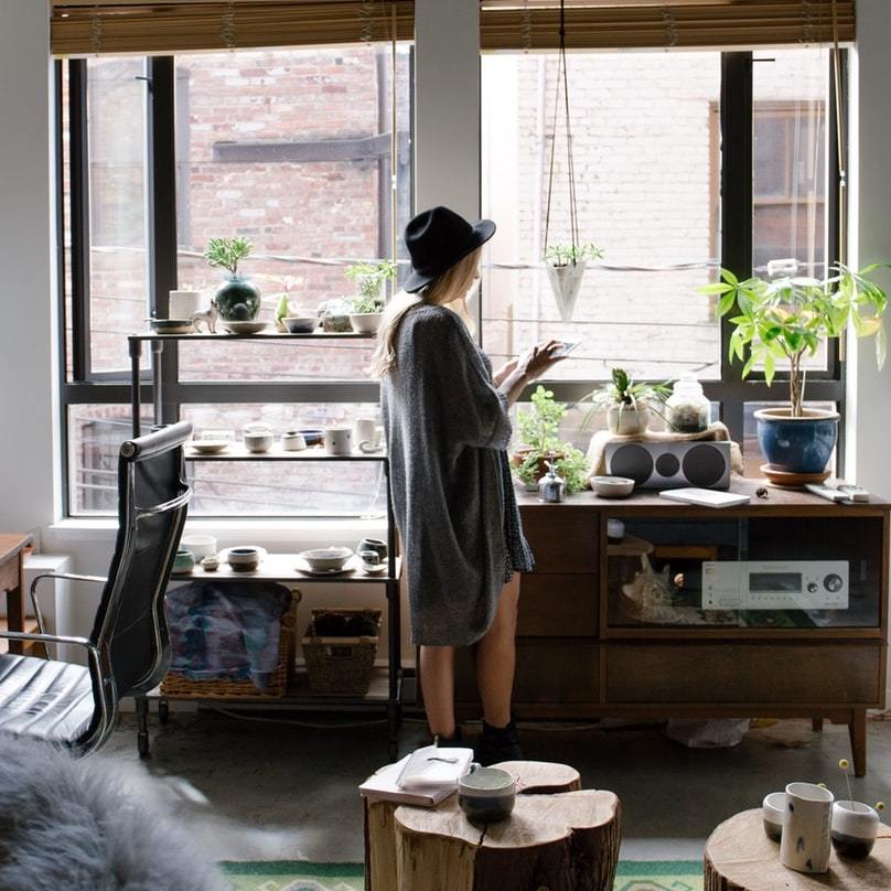 woman in apartment with stereo, plants desk chair