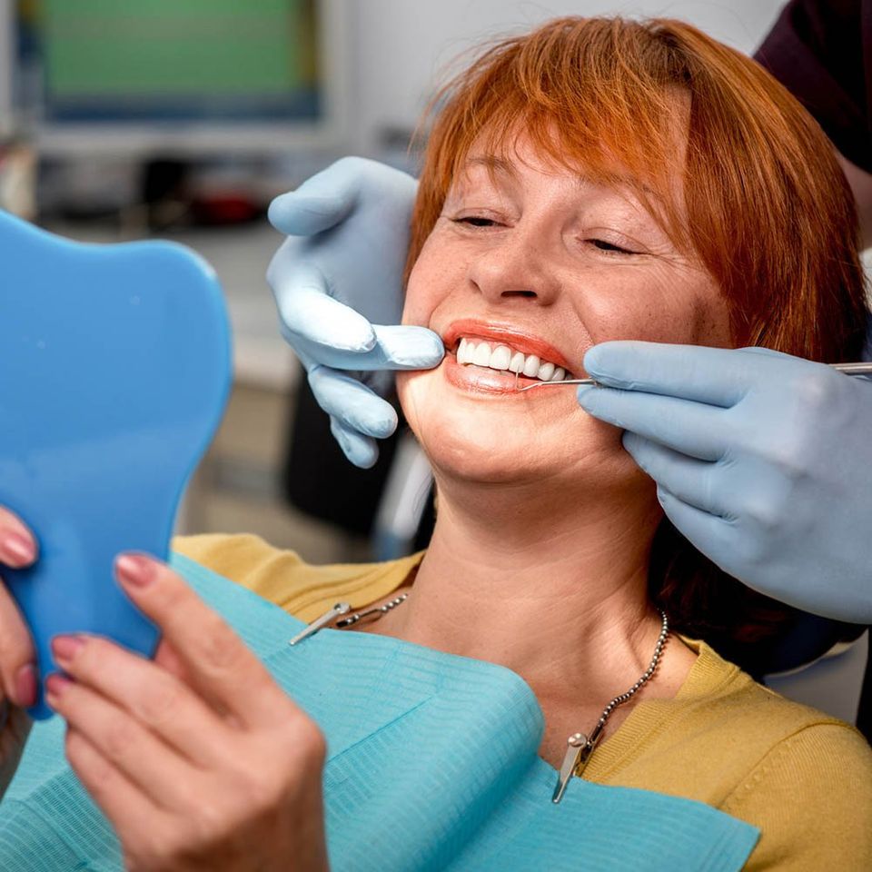 Woman Looking at Her Teeth Through the Mirror — Hickory, NC — McDonald Family Dentistry Woman Looking at Her Teeth Through the Mirror — Hickory, NC — McDonald Family Dentistry