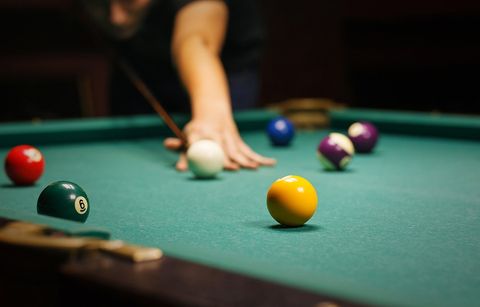 A person is playing pool on a pool table.